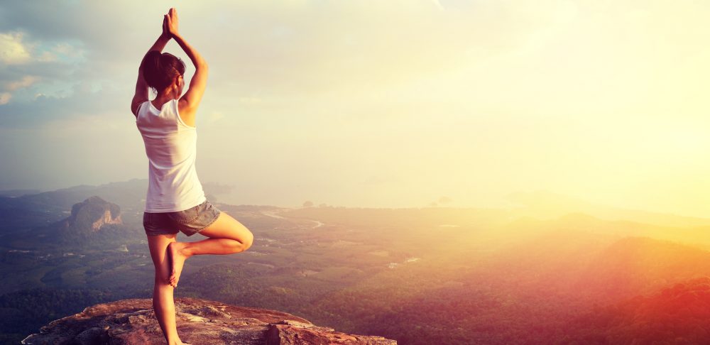 independent girl doing yoga on a mountain top