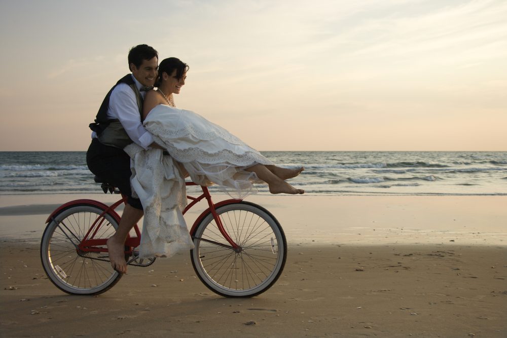 Newlyweds right a bike on the beach