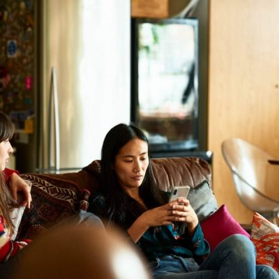Should You Let Your Ex Come To You? woman-sitting-on-sofa-with-friend-using-cell-phone